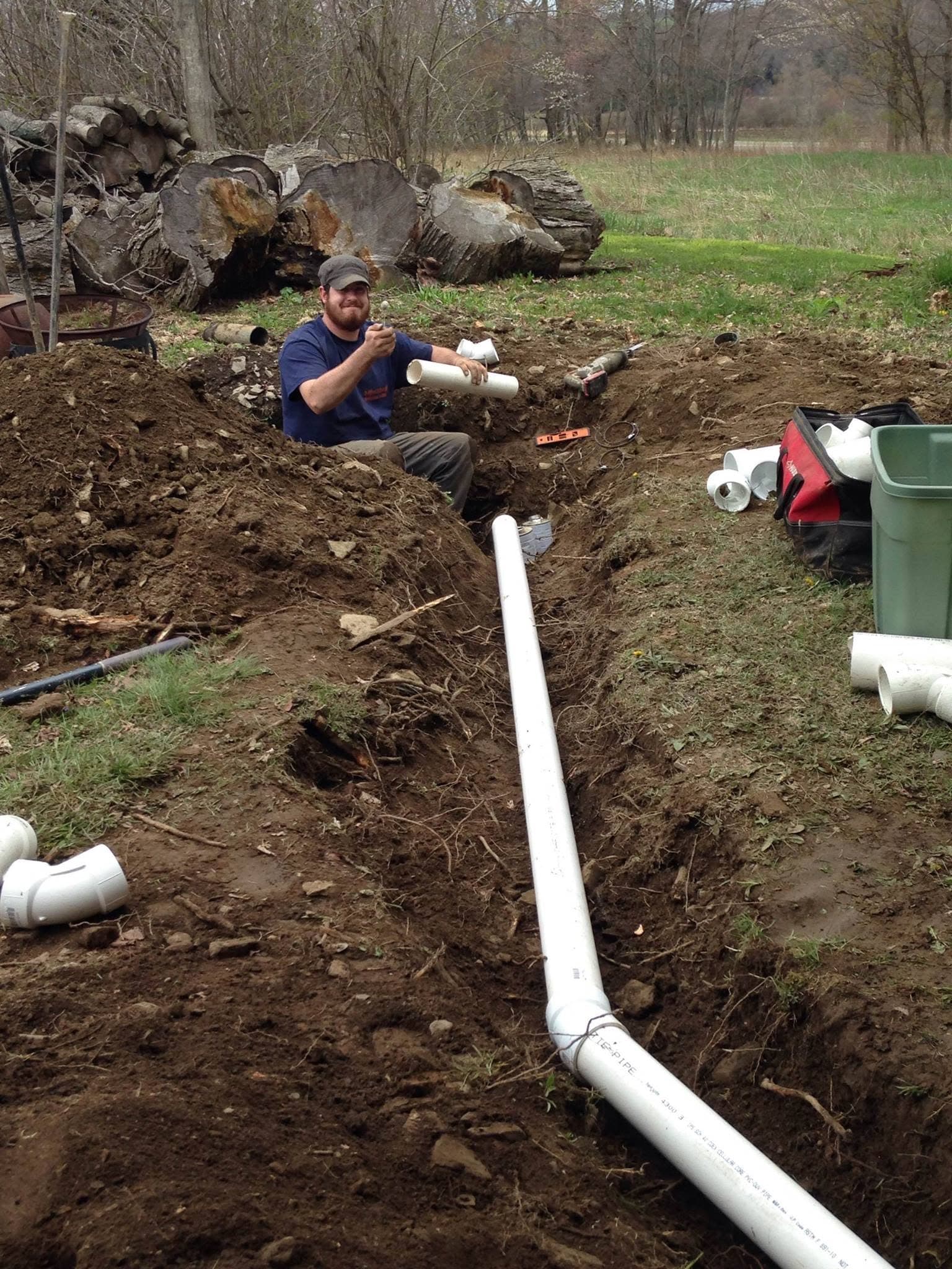 Technician installing new pipe in an open trench